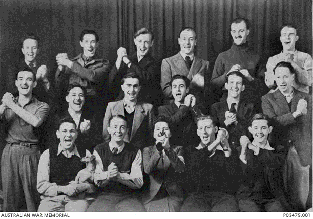Black and white photo of a group of people in war time dress.  All smiling